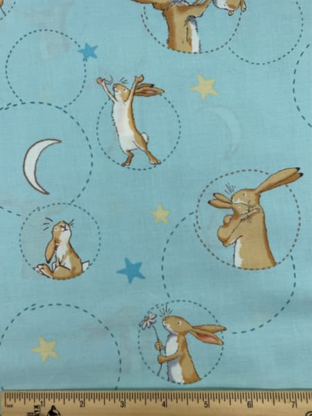 Nut Brown Hare with flower on Blue Quilting Fabric by Sam McBratney from Guess How Much I Love You for Clothworks