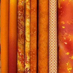 A pile of orange quilting fabrics