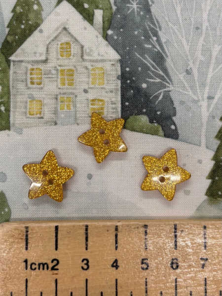 Gold glitter star button by Trimits, 18mm, shown against a winter fabric background with ruler for scale.