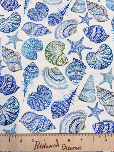 Wonders of the Ocean shells quilting fabric by Jason Yenter for In the Beginning Fabrics UK, featuring blue and green seashells and starfish on a white background.