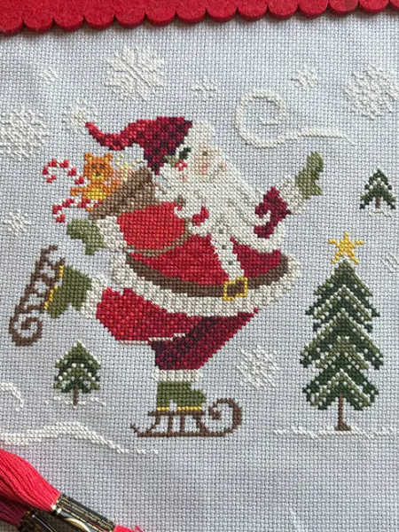 Love Poppet skating Santa counted cross stitch design with snowy trees and Christmas treats