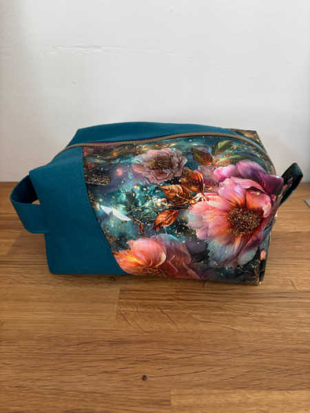 Side view of teal and floral Densa Dopp Kit bag with carrying handle