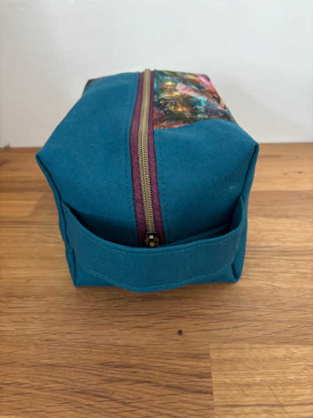 End view of Densa Dopp Kit showing zip and teal carrying handle