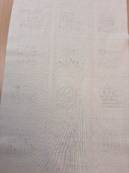 Close-up of Appleby Farm pre-printed embroidery blocks with cottage garden and countryside motifs on natural cream fabric.