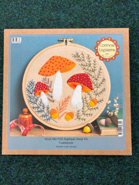 Corinne Lapierre Toadstools Wool Felt Appliqué Hoop Kit featuring orange and red mushrooms with embroidered woodland foliage.